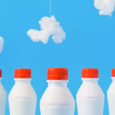 Bottles of milk with blue sky with clouds background 